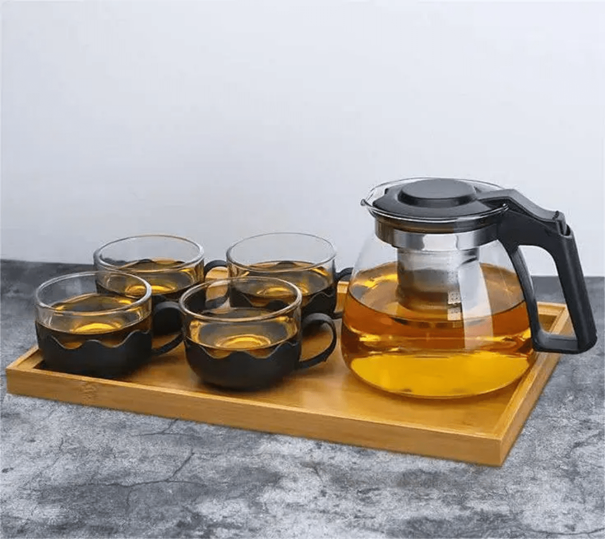 Glass teapot and 4 cups with boiling water and herbals inside