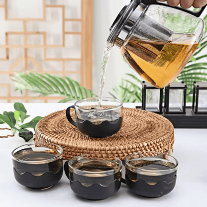 Glass teapot and 4 cups with boiling water and tea inside